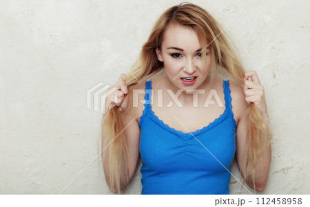 Blond woman teenage girl showing her damaged dry hair Blond woman teenage girl showing her damaged dry hair 112458958