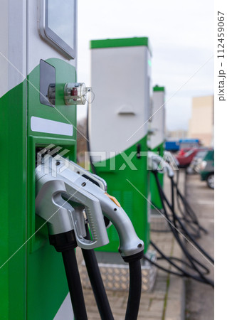 Car parking with charging stations near a multi-storey apartment building. 112459067