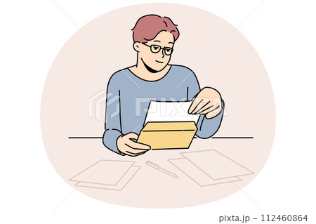 Man in glasses reading letter at table 112460864