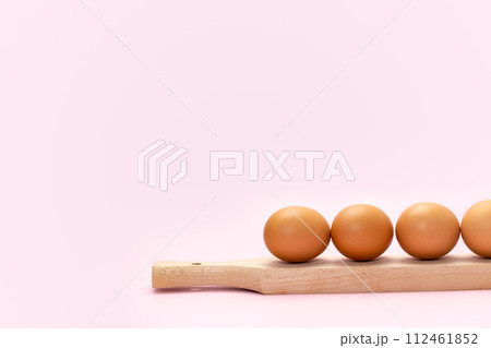Row of eggs on wooden plank 112461852