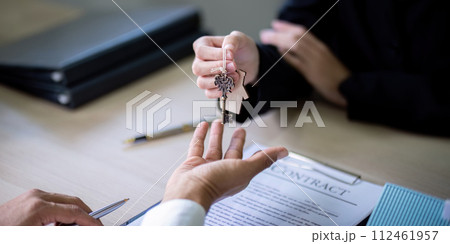 Real estate agent agree to buy a home and give key to client at agency office. Concept agreement Real estate agent agree to buy a home and give key to client at agency office. Concept agreement 112461957