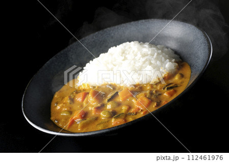 豚肉、かぼちゃ、人参などの野菜が沢山入った熱々カレーライスを黒背景で撮影 112461976