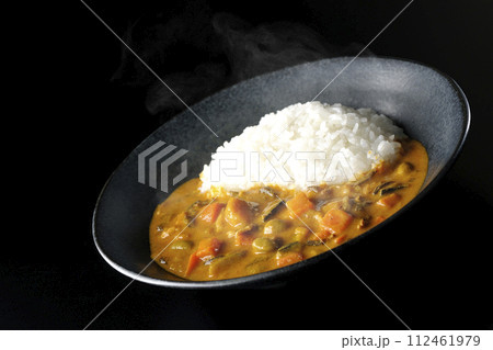 豚肉、かぼちゃ、人参などの野菜が沢山入った熱々カレーライスを黒背景で撮影 112461979