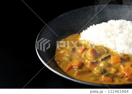 豚肉、かぼちゃ、人参などの野菜が沢山入った熱々カレーライスを黒背景で撮影 112461984