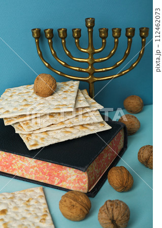 Matzo, nuts, hanukkiah and Torah on blue background, close up Matzo, nuts, hanukkiah and Torah on blue background, close up 112462073