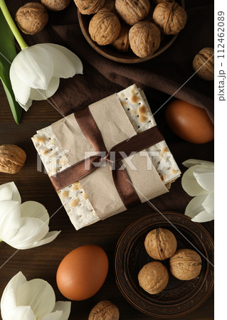 Matzo, eggs, nuts and flowers on towel on wooden background, top view 112462089