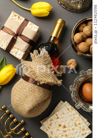 Matzo, nuts, hanukkiah, bottle of wine and flowers on gray background, top view Matzo, nuts, hanukkiah, bottle of wine and flowers on gray background, top view 112462098