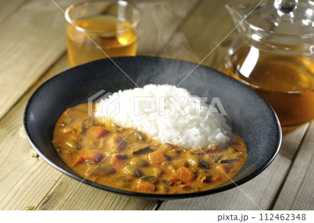 豚肉、かぼちゃ、人参などの野菜が沢山入った熱々カレーライスとお茶 112462348