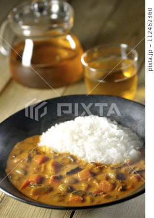 豚肉、かぼちゃ、人参などの野菜が沢山入った熱々カレーライスとお茶 豚肉、かぼちゃ、人参などの野菜が沢山入った熱々カレーライスとお茶 112462360