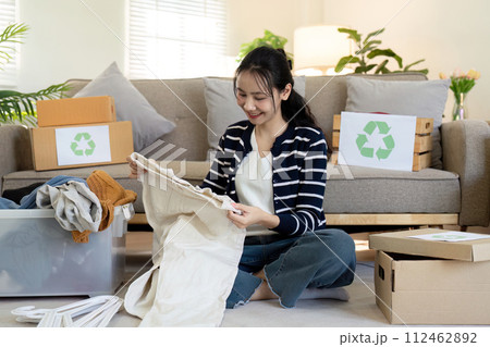 Woman pack box with used clothes for reuse. Reusing, recycling material and reducing waste in fashion, second hand apparel idea. Circular fashion, zero waste concept 112462892