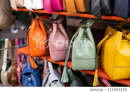 Close up of different leather bags on market. Modern colorful bags for sale. Womanly accessories 112463339