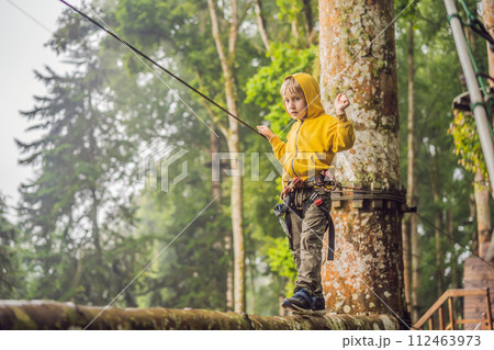 Little boy in a rope park. Active physical recreation of the child in the fresh air in the park. Training for children Little boy in a rope park. Active physical recreation of the child in the fresh air in the park. Training for children 112463973