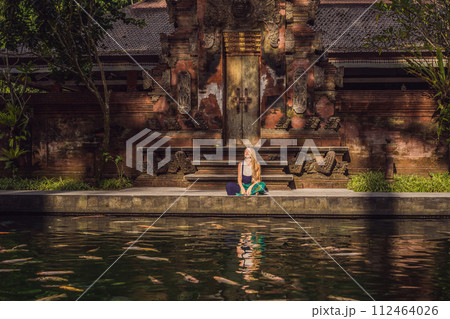 Woman feeding beautiful coloured fish in pond temple on Bali 112464026