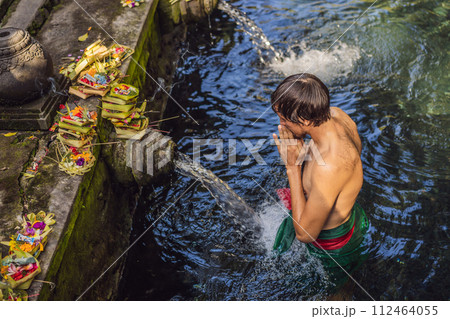 Man in holy spring water temple in bali. The temple compound consists of a petirtaan or bathing structure, famous for its holy spring water Man in holy spring water temple in bali. The temple compound consists of a petirtaan or bathing structure, famous for its holy spring water 112464055