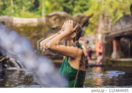 Woman in holy spring water temple in bali. The temple compound consists of a petirtaan or bathing structure, famous for its holy spring water 112464095