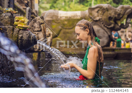 Woman in holy spring water temple in bali. The temple compound consists of a petirtaan or bathing structure, famous for its holy spring water 112464145
