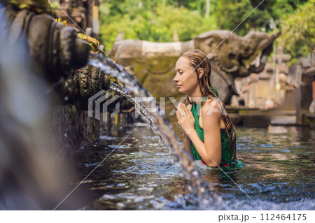 Woman in holy spring water temple in bali. The temple compound consists of a petirtaan or bathing structure, famous for its holy spring water 112464175