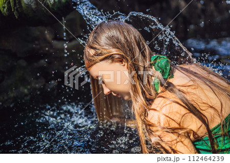 Woman in holy spring water temple in bali. The temple compound consists of a petirtaan or bathing structure, famous for its holy spring water 112464239