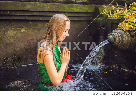 Woman in holy spring water temple in bali. The temple compound consists of a petirtaan or bathing structure, famous for its holy spring water 112464252