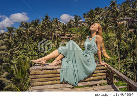 Beautiful young woman walk at typical Asian hillside with rice farming, mountain shape green cascade rice field terraces paddies. Ubud, Bali, Indonesia. Bali travel concept Beautiful young woman walk at typical Asian hillside with rice farming, mountain shape green cascade rice field terraces paddies. Ubud, Bali, Indonesia. Bali travel concept 112464684