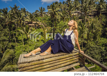 Beautiful young woman walk at typical Asian hillside with rice farming, mountain shape green cascade rice field terraces paddies. Ubud, Bali, Indonesia. Bali travel concept 112464704