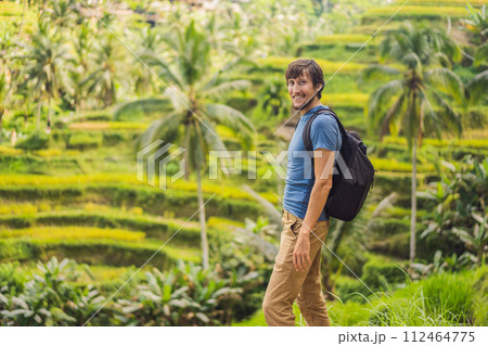 Male tourist with a backpack goes on the rice field 112464775