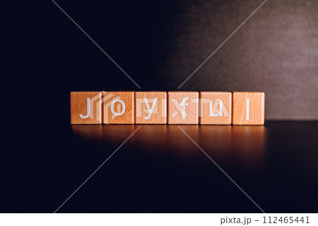 Wooden blocks form the text "Joyful" against a black background. Wooden blocks form the text "Joyful" against a black background. 112465441