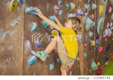 little boy climbing a rock wall in special boots. indoor 112465748