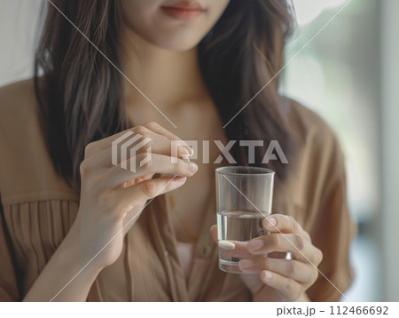 Smiling woman holding glass of water, drinking healthily 112466692