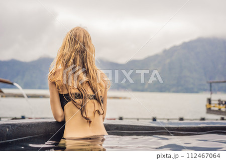 Geothermal spa. Woman relaxing in hot spring pool against the lake. hot springs concept 112467064