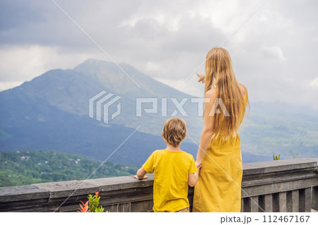 Mom and son tourists on background looking at Batur volcano. Indonesia. Traveling with kids concept Mom and son tourists on background looking at Batur volcano. Indonesia. Traveling with kids concept 112467167