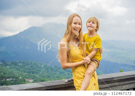 Mom and son tourists on background looking at Batur volcano. Indonesia. Traveling with kids concept Mom and son tourists on background looking at Batur volcano. Indonesia. Traveling with kids concept 112467172