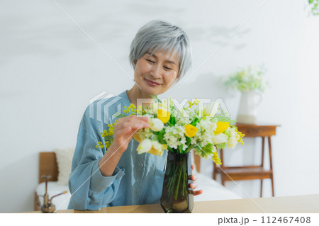 花を花瓶に飾るシニア女性 花を花瓶に飾るシニア女性 112467408