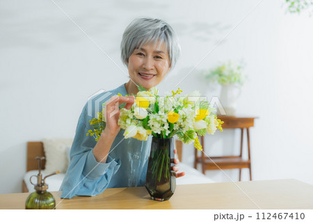 花を花瓶に飾るシニア女性 花を花瓶に飾るシニア女性 112467410