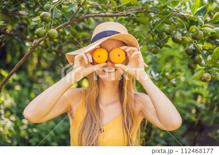 Portrait of Attractive Farmer Woman is Harvesting Orange in Organic Farm, Cheerful Girl in Happiness Emotion While Reaping Oranges in The Garden, Agriculture and Plantation Concept 112468177