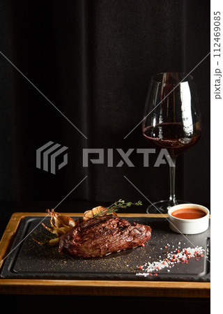 Succulent grilled beef steak with red wine, seasonings, fresh rosemary and grilled vegetables on cutting board 112469085