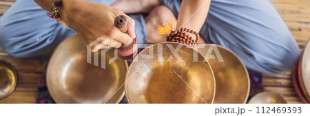 Woman playing on Tibetan singing bowl while sitting on yoga mat against a waterfall. Vintage tonned. Beautiful girl with mala beads meditating BANNER, LONG FORMAT Woman playing on Tibetan singing bowl while sitting on yoga mat against a waterfall. Vintage tonned. Beautiful girl with mala beads meditating BANNER, LONG FORMAT 112469393