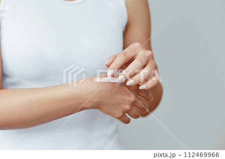 Closeup shot of woman hands holding cream and applying moisturizing hand cream. Beautiful female hands with cream. Hand Skin Care. A woman uses body lotion on your arms. Beauty And Body Care Concept 112469966