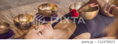 BANNER, LONG FORMAT Nepal Buddha copper singing bowl at spa salon. Young beautiful woman doing massage therapy singing bowls in the Spa against a waterfall. Sound therapy, recreation, meditation BANNER, LONG FORMAT Nepal Buddha copper singing bowl at spa salon. Young beautiful woman doing massage therapy singing bowls in the Spa against a waterfall. Sound therapy, recreation, meditation 112470025