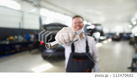 Male repairman holding wrench in car workshop closeup Male repairman holding wrench in car workshop closeup 112470682