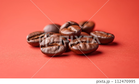 Dark Roasted Coffee Beans Close-up on Red Background, Shiny Oily Beans Piled in Random Pattern 112470995