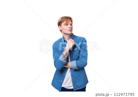 a young red-haired guy in a blue denim shirt actively gesticulates. advertising concept a young red-haired guy in a blue denim shirt actively gesticulates. advertising concept 112471795
