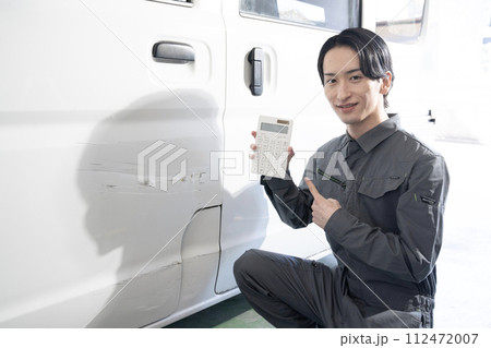 傷ついた車の修理の見積もりをする作業員 傷ついた車の修理の見積もりをする作業員 112472007