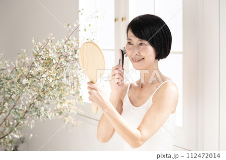 ビューティ 窓辺で鏡を見て美顔器を使う女性 ビューティ 窓辺で鏡を見て美顔器を使う女性 112472014