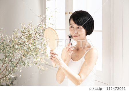 ビューティ 窓辺で鏡を見て美顔器を使う女性 ビューティ 窓辺で鏡を見て美顔器を使う女性 112472061