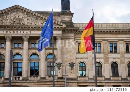 National flag of Germany and flag of the European Union are fluttering in the wind against background of Bundestag building. Government building in Berlin 112472516
