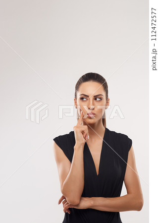 Close-up of curious pretty girl, looking upper left corner at something interesting, standing over white background 112472577