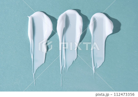 Three strokes of white cream on a blue background. 112473356