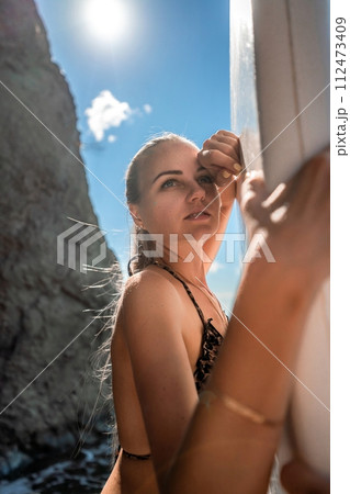 Woman in black bikini sap sea. Portrait of a happy girl on the background of a surfboard in the sea on a sunny summer day 112473409