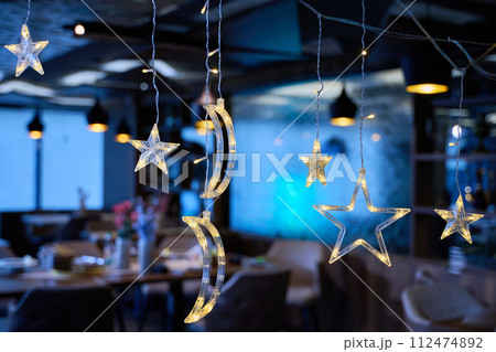 In a modern restaurant, the ambiance is transformed by the presence of sparkling Islamic symbolic Ramadan decorations, creating a festive and culturally rich atmosphere In a modern restaurant, the ambiance is transformed by the presence of sparkling Islamic symbolic Ramadan decorations, creating a festive and culturally rich atmosphere 112474892